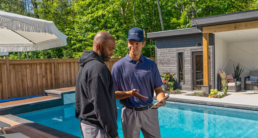 Pool technician discussing pool maintenance with client near a pool.
