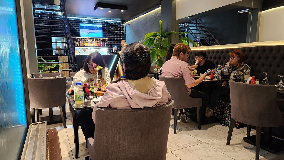 Las mesas en el angosto restaurante de sushi están ocupadas por jóvenes que disfrutan su cena.