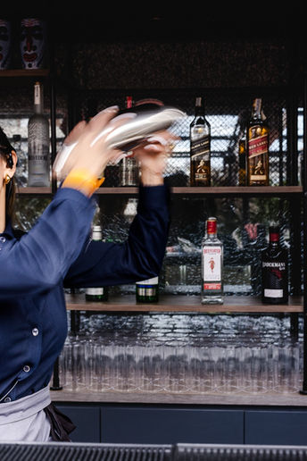 Manos de una bartender agitando un cocktail en la barra de una terraza en Cala San Miguel Ibiza Resort