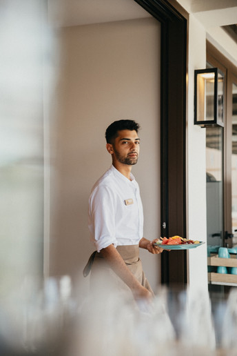 Un camarero que lleva en la mano un plato con fruta fresca en el Resort Cala San Miguel Ibiza