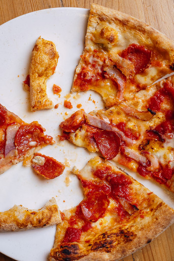 Apetecible pizza mordida con ingredientes como chorizo y bacon en el restaurante Pizzería Araldo 