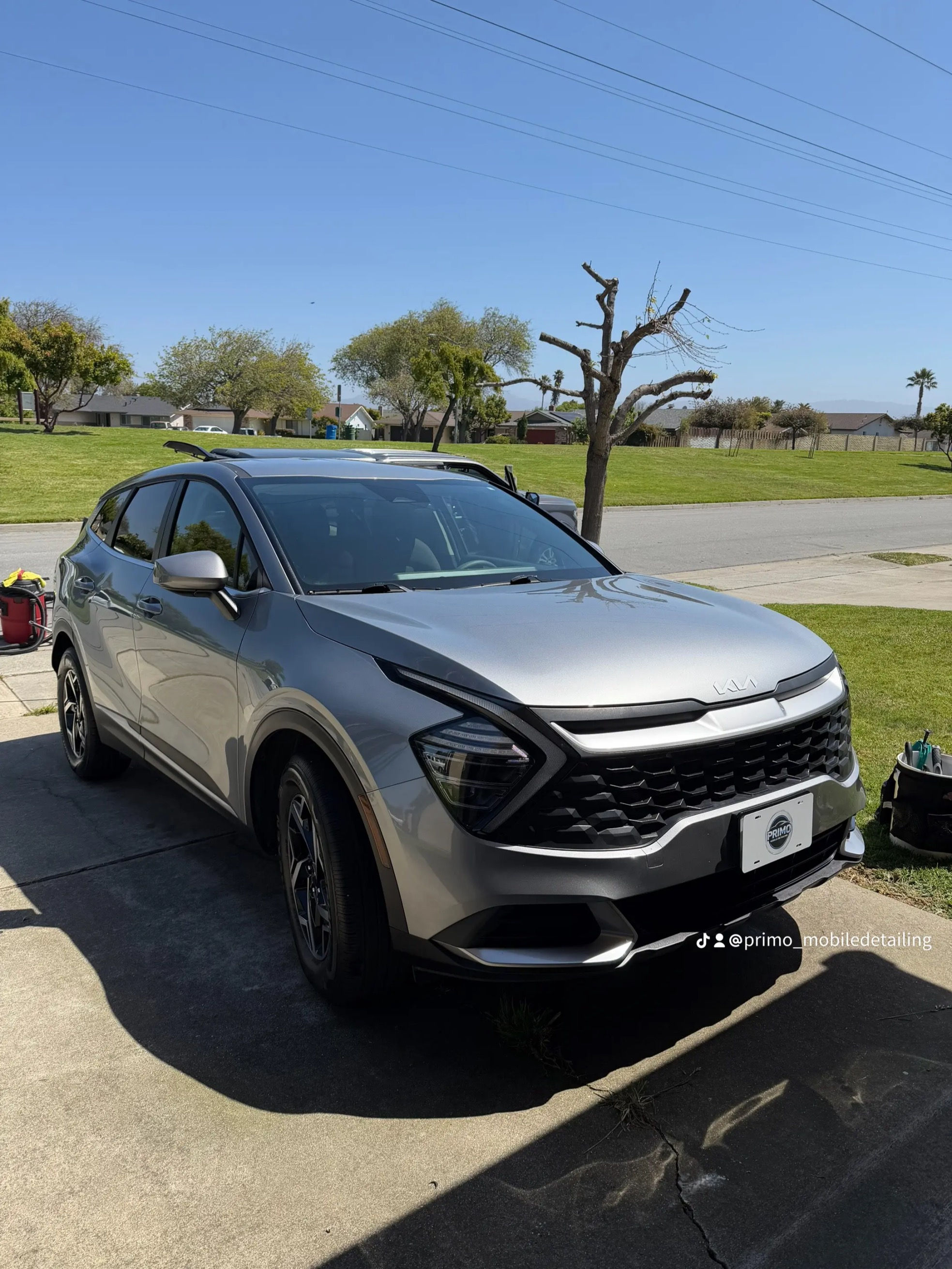 Silver Kia Sportage SUV on a sunny driveway