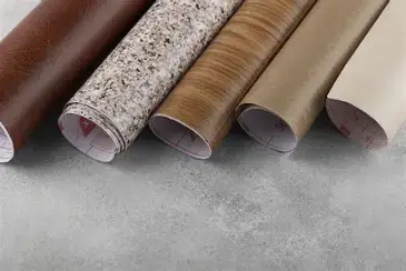 Multiple rolls of sheet vinyl in different colors and patterns on concrete-like surface, landscape