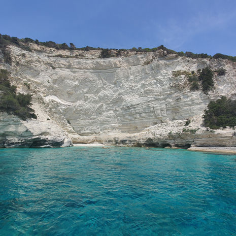 Dramatic white limestone cliffs and turquoise waters of the Paxos west coast in Greece.