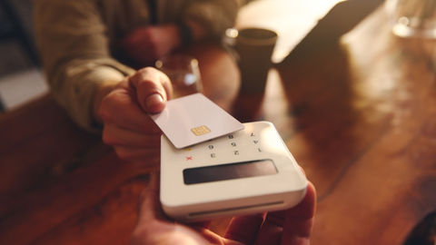 A person using their debit card to pay in a café. 