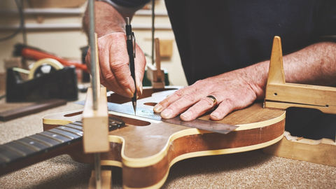A man fixing a guitar in a workshop.  