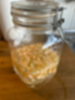 Glass jar with diced apples in liquid, sealed with a metal latch. Placed on a wooden countertop with a paper towel roll in the background.