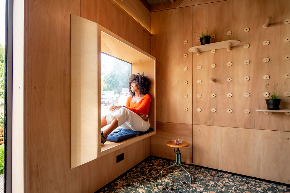 Woman sitting in cozy nook inside London garden room office pod.
