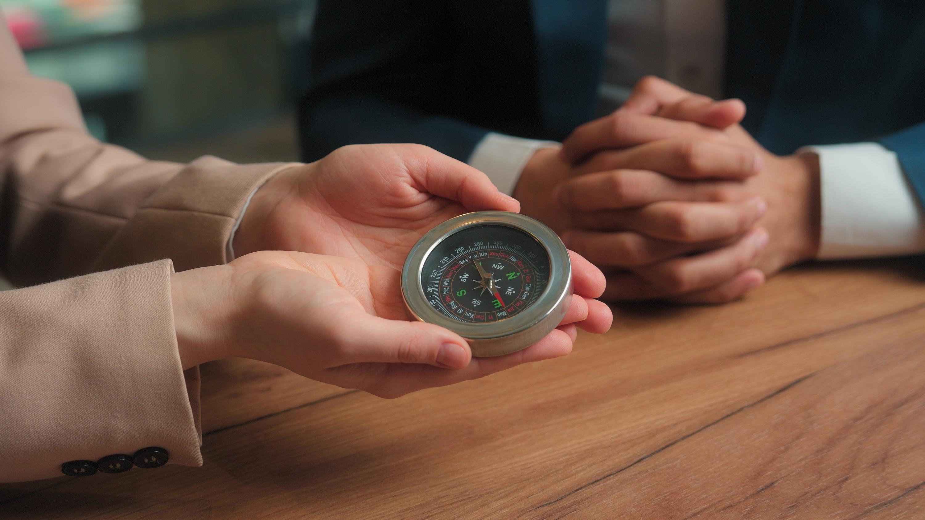 Hands holding a compass over a wooden table