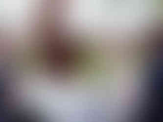 Nancy and Ammar smile joyfully during their wedding ceremony as a lace cloth is held above them in a traditional Persian sofreh aghd setup. A table in front of them is adorned with symbolic items, including a mirror, sweets, and twisted candles during their Olin Park wedding.