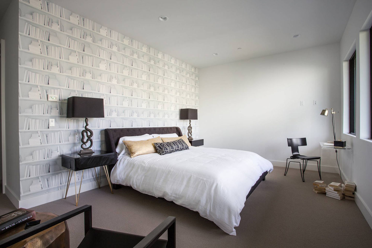 Modern bedroom with white bedding, patterned wallpaper