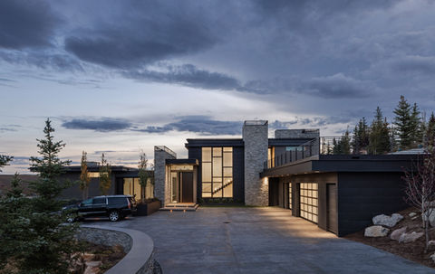 Modern luxury home at dusk, showcasing sleek design and stone facade