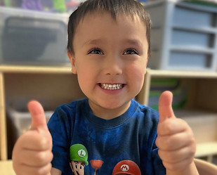 Smiling preschool boy with thumbs up