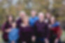 Family of adults and children wearing blue and maroon shirts.