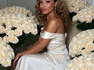 a woman sitting in a white satin dress among flowers