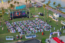"Outdoor corporate event with stage, lighting, and large digital screens and ausience