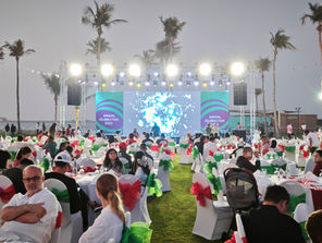 Outdoor corporate event with stage, lighting, and large digital screens