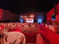 Outdoor corporate event with stage, lighting, and large digital screens