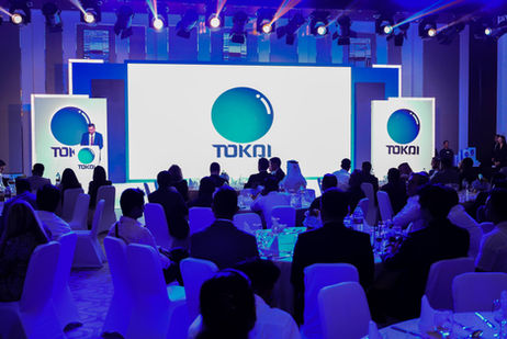 Company branding displayed on stage screens at a corporate gala dinner.
