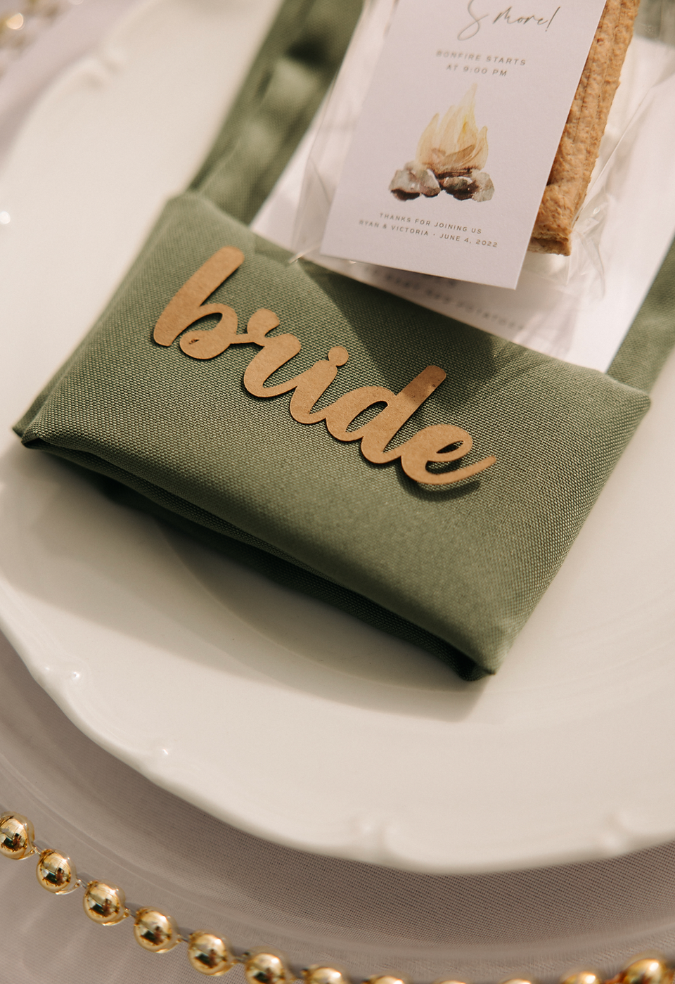 'Bride' die cut out of brown cardstock on a sage green napking place setting with gold accents