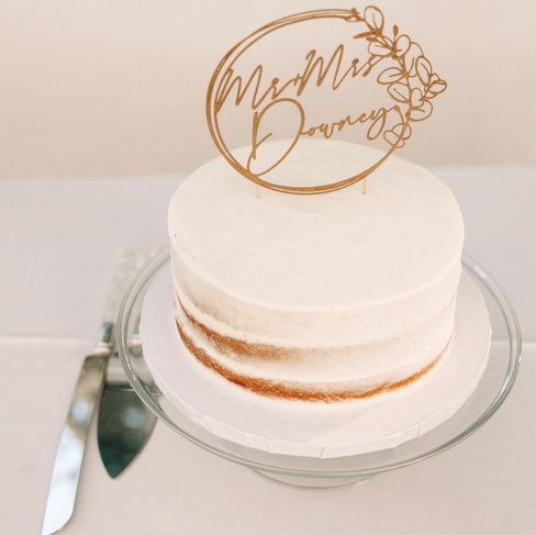 'dirty iced' cake in white icing with a brown card stock cake topper that reads Mr and Mrs Downey