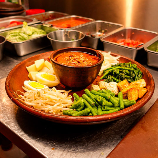 Traditional Indonesian Gado Gado salad with peanut sauce, fresh vegetables, tofu, egg, and rice cakes, served at Bali Satay House in London.