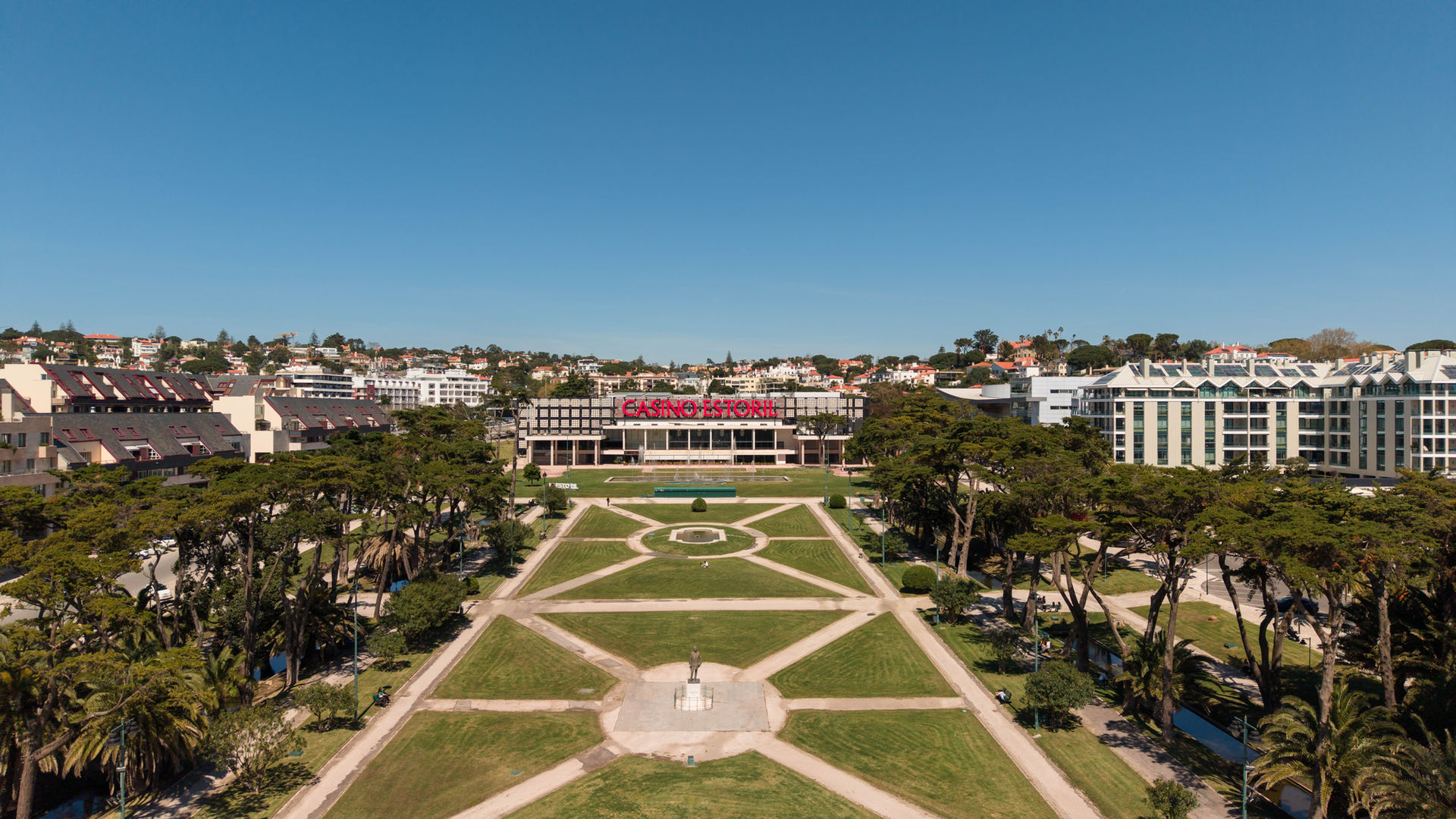 Aerial view of a formal garden with geometric patterns and city buildings casino do estoril
