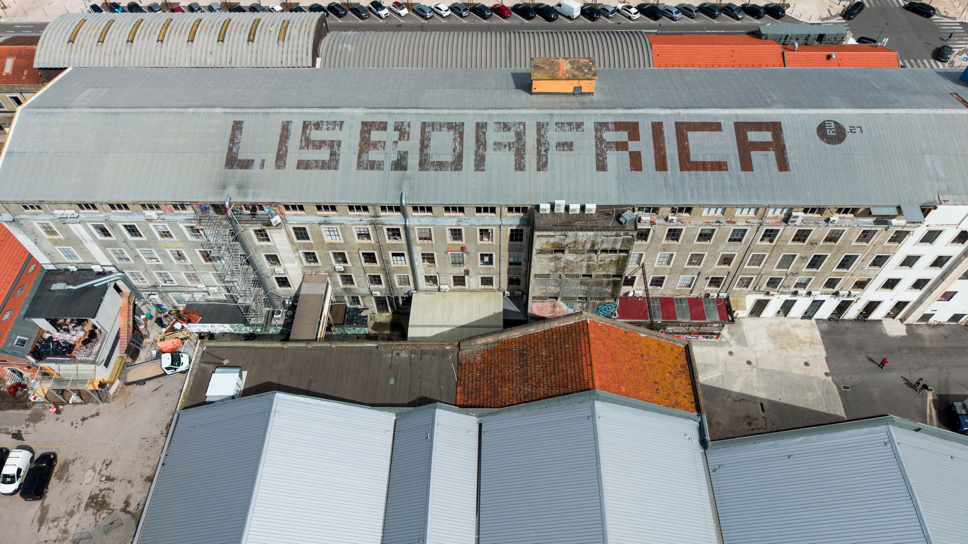 Aerial view of 'LISBOAFRICA' text on a large building roof in lisbon