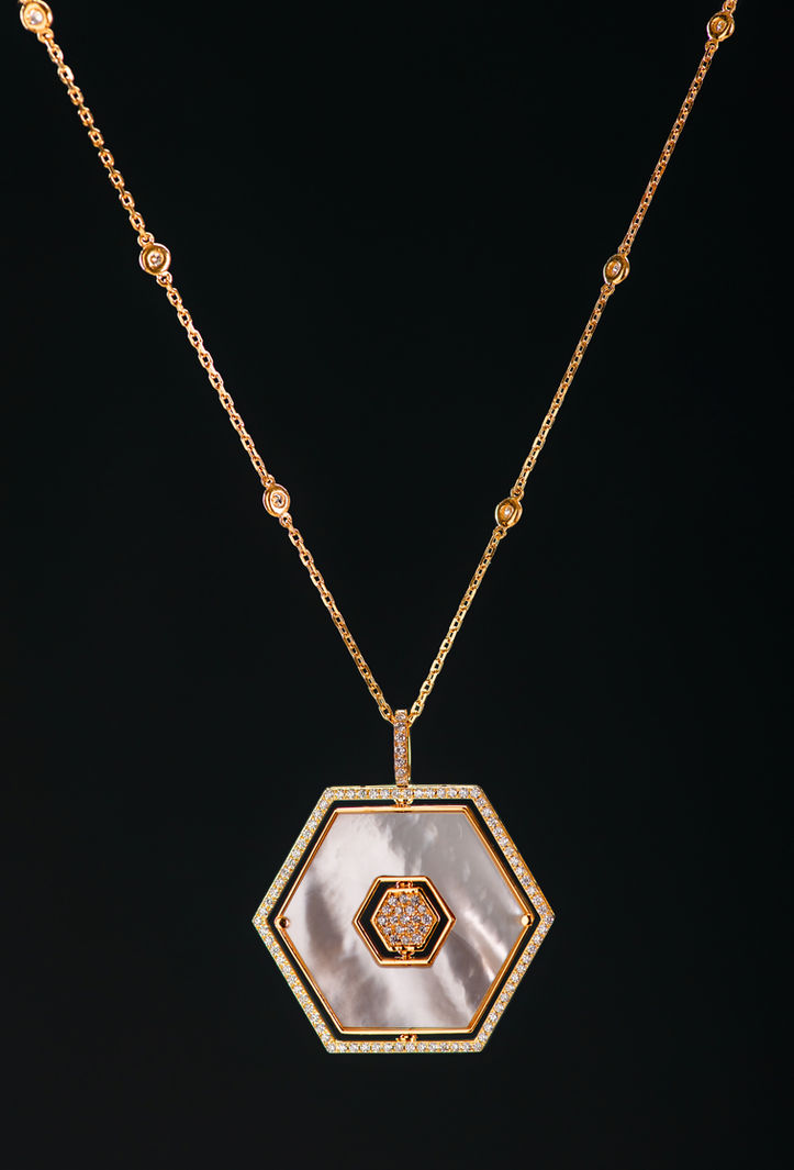 gold octagon pendant on clean black surface shot by Octo Studio