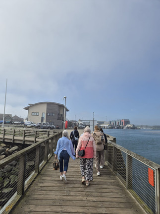 Women exploring Amble Harbour, Northumberland seaside town, scenic coastal walk, independent shops and waterfront views in “The Friendliest Port