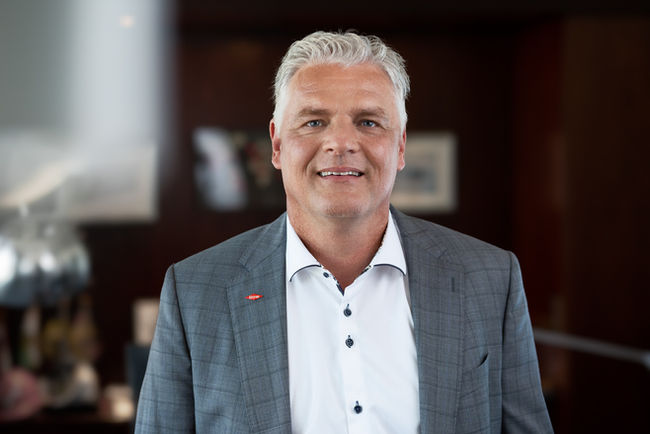 Ein Porträt eines CEOs in einem klassischen Büroambiente. Der CEO trägt Businesskleidung und blickt konzentriert und souverän in die Kamera, was eine professionelle und entschlossene Ausstrahlung vermittelt. Der Hintergrund zeigt dezent ein Bürointerieur, das den Corporate-Charakter des Bildes unterstreicht und eine dynamische, geschäftliche Atmosphäre schafft.