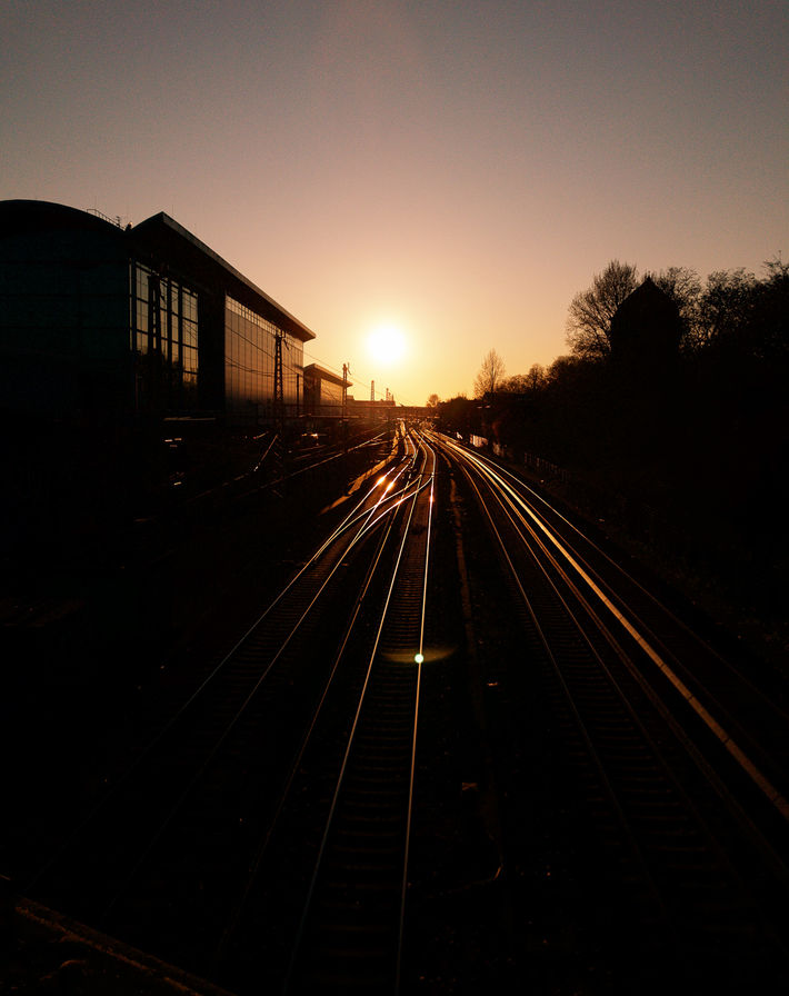 Sunset Over Railroad Tracks Leading Past Modern Urban Buildings
