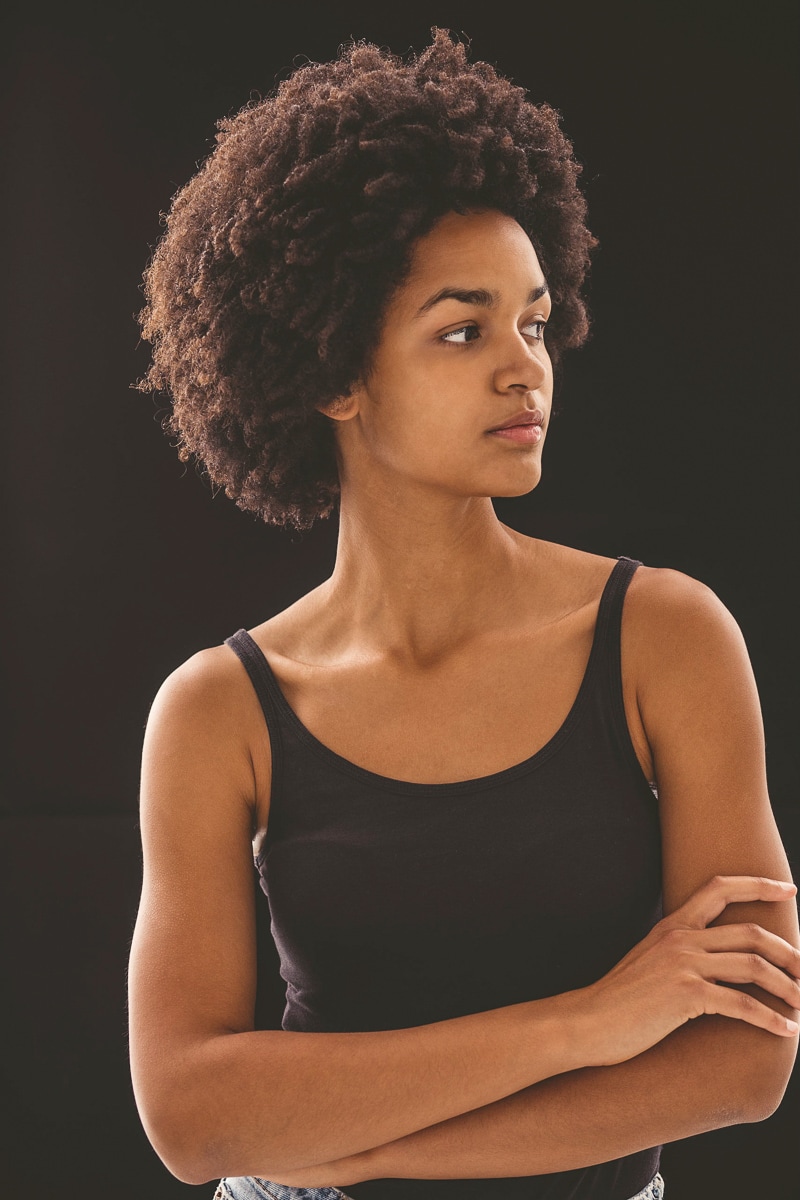 Young Woman with Natural Curly Hair Posing Against a Dark Studio Background