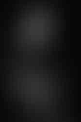 A monochromatic image capturing a woman in fashionable attire, exuding style and confidence, against a dark backdrop.