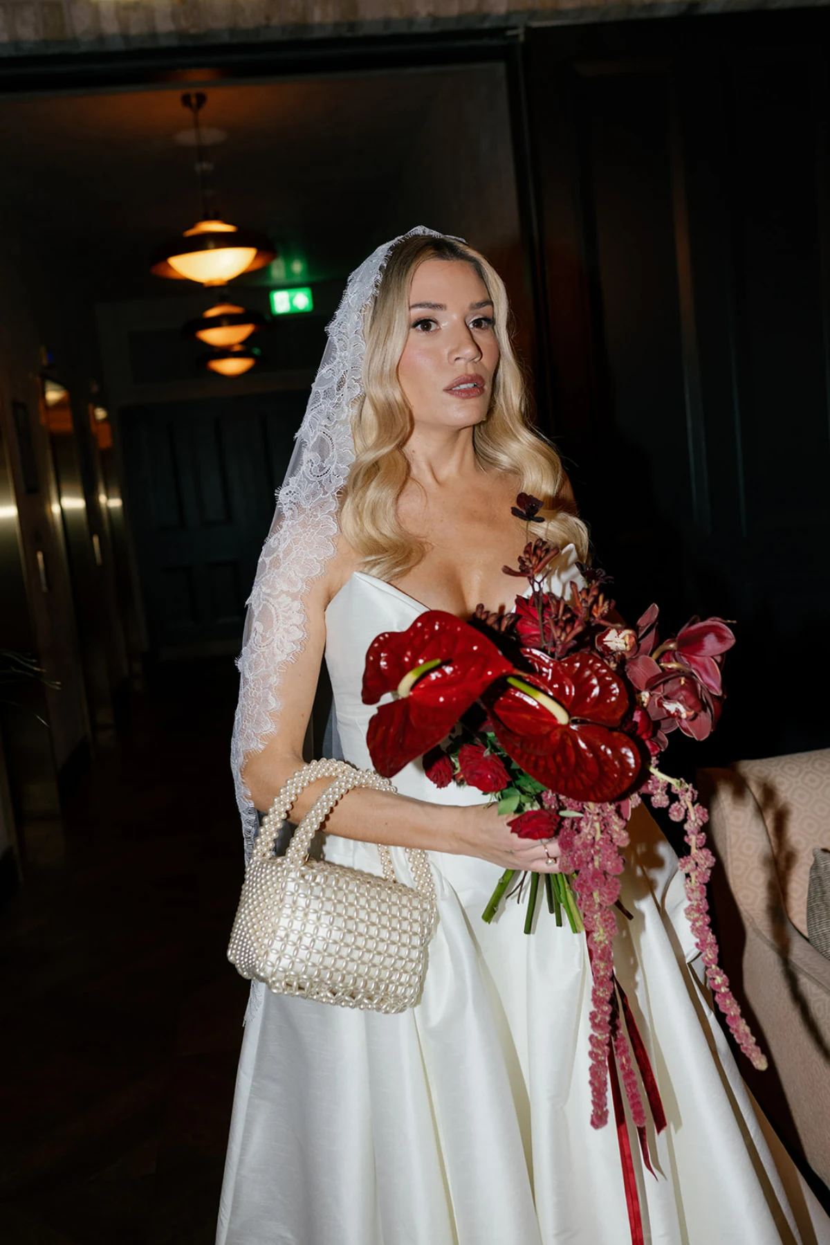 A bride carries a bouquet of deep burgundy flowers