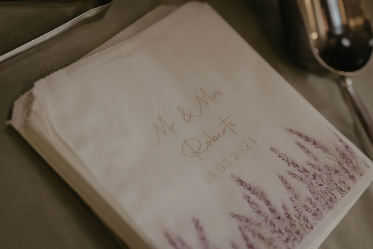 A close up of some paper sweet bags featuring a design of lavender, and the words "Mr & Mrs Roberts 18.05.2024".