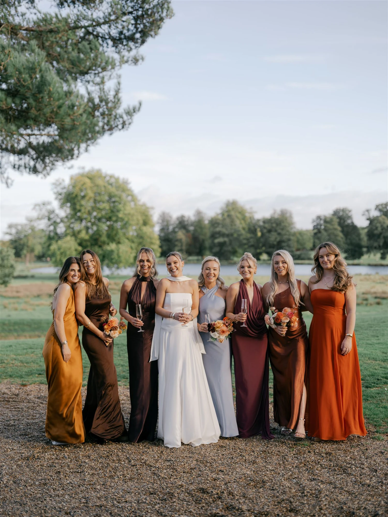Bridesmaids posing in a line outside with the bride.