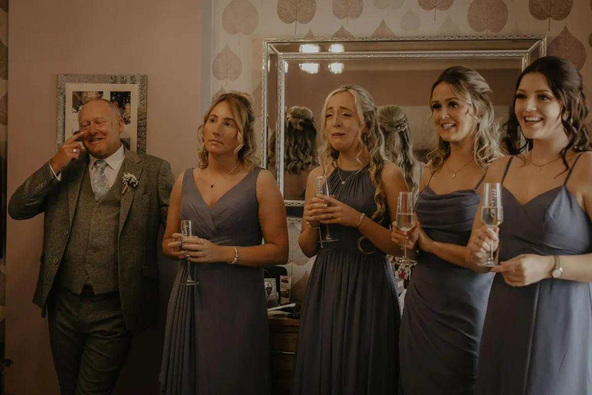 A father and bridesmaids wait to see a bride on her wedding day. Happy tears and hopefuly joy. Suffolk wedding photography by Mikaela Jade.