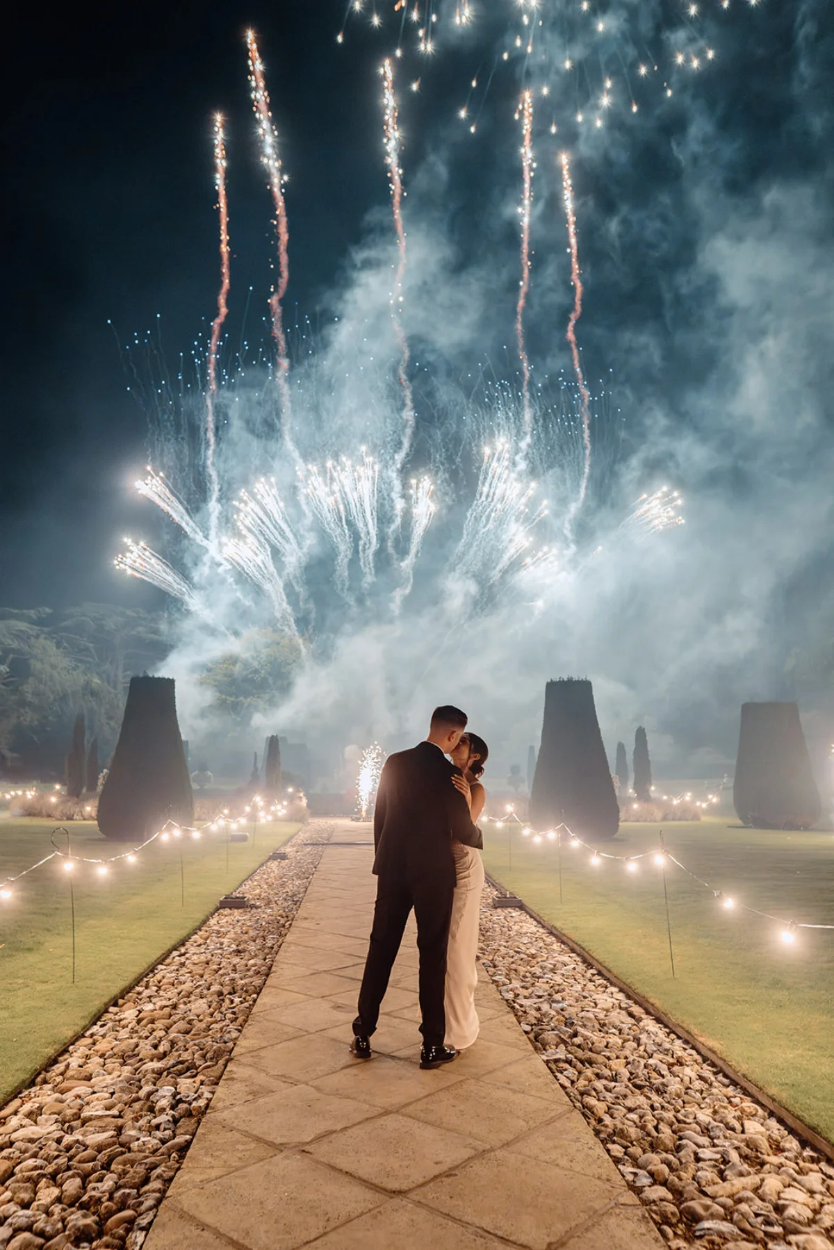 A couple kiss outisde as fireworks light up the sky at Hengrave Hall, Suffolk.