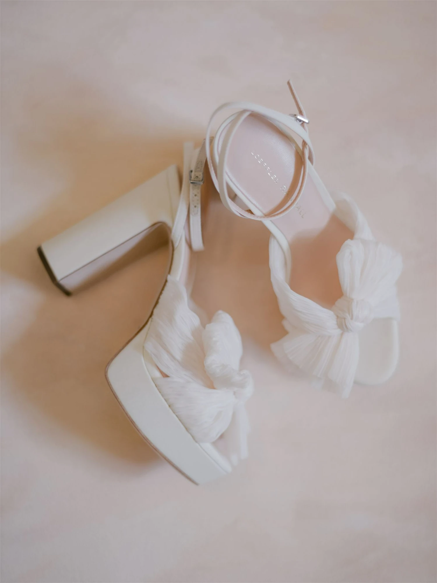 A bride facing a window wearing a long wedding dress and veil - there is a soft glow to the image.