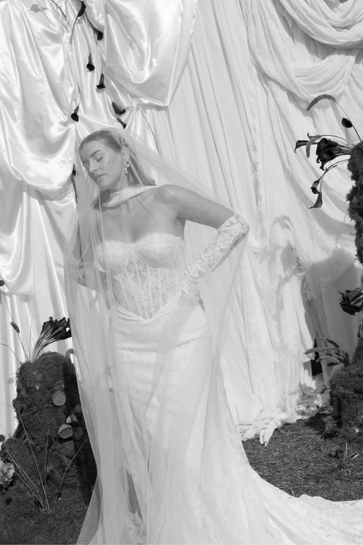 A bride lposes in a lace wedding dress and chiffon veil, wearing makeup by Suffolk makeup artist Emily Chantal.