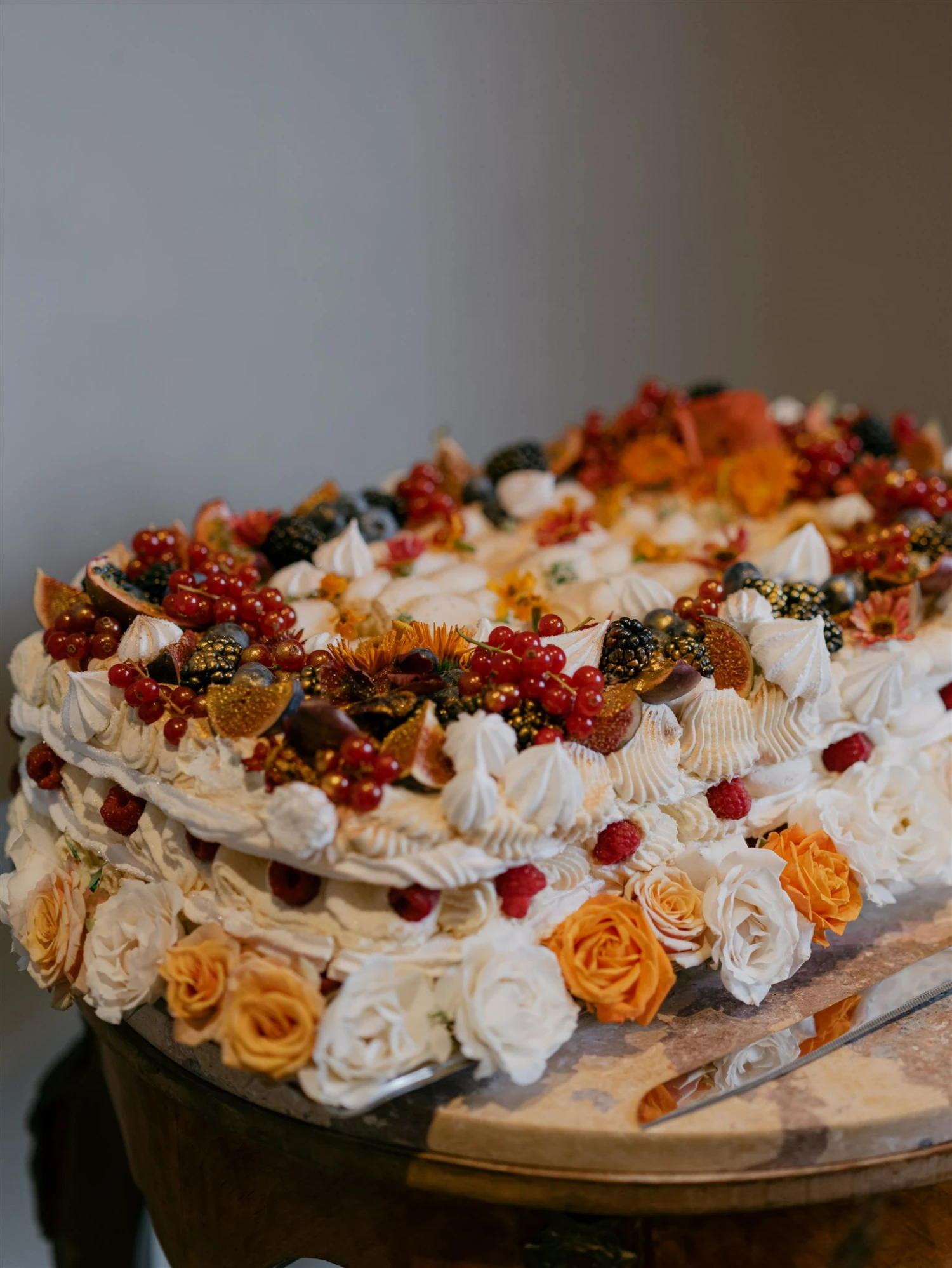 A rectangular wedding cake make with meringue and topped with figs, berries and flowers.