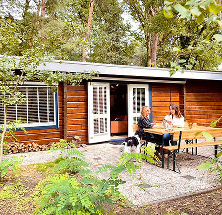 Boshuisje en vakantiehuisje De Boskeet met terras, eettafel en groene tuinomgeving in Noord-Limburg
