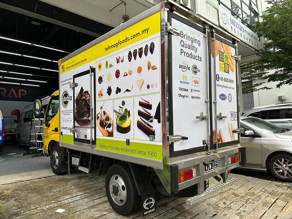 Yellow delivery truck with chocolate-themed graphics and "tehmagfoods.com.my" parked outside a building. Text: "Bringing Quality Products."