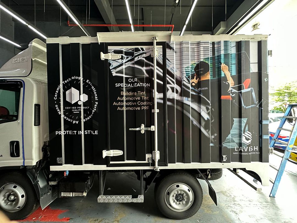 Truck with black and white design featuring a worker applying tint to a car window. Text: "Our Specialization" and "Lavish Nano Ceramic."