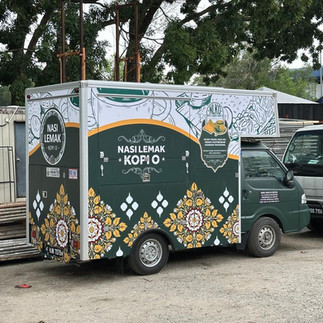 Green mini lorry with festive Raya-themed lorry sticker design, showcasing professional sticker lori installation for branding during seasonal events.