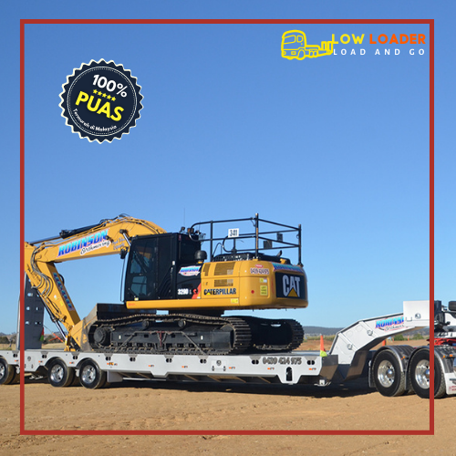 Low loader truck menurunkan jentera di tapak pembinaan.