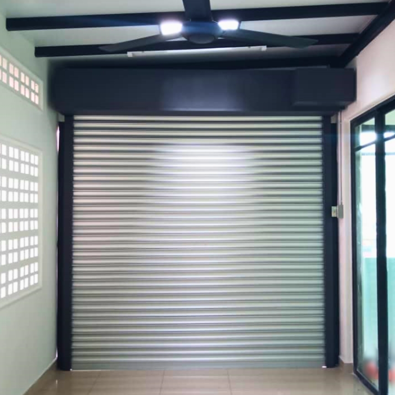 Roller shutter technician greasing track and checking motor in Bangi