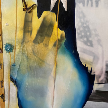 Detail 6: This image is of an abstract outline of a ship which references the slaves brought to the Americas. In the background, an American flag, horizontal lines representing the American flag. One polymer butterfly, one resin flower set in blue to represent democracy, and one set of angels wings set in resin polymer. The wings represent the lives lost on durithe insurrection. The position of Ms. Gormans hand is representative of a mudra called ARDHA PARIGHASANA with ARDHA PATAKA MUDRA
This pose symbolizes your ability to bridge differences and distances and links the spiritual to the material. “May I be a bridge for those who feel separate from you, Divine Mother. May I provide peace to others with my words and comfort to others with my actions.