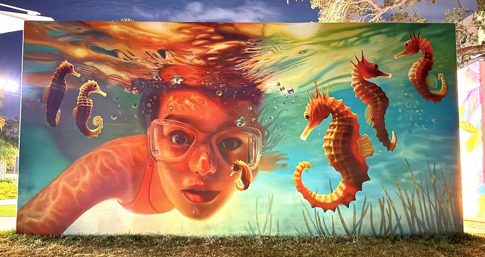 Naomi Haverland mural of a child underwater surrounded by seahorses in a luminous ocean scene.
